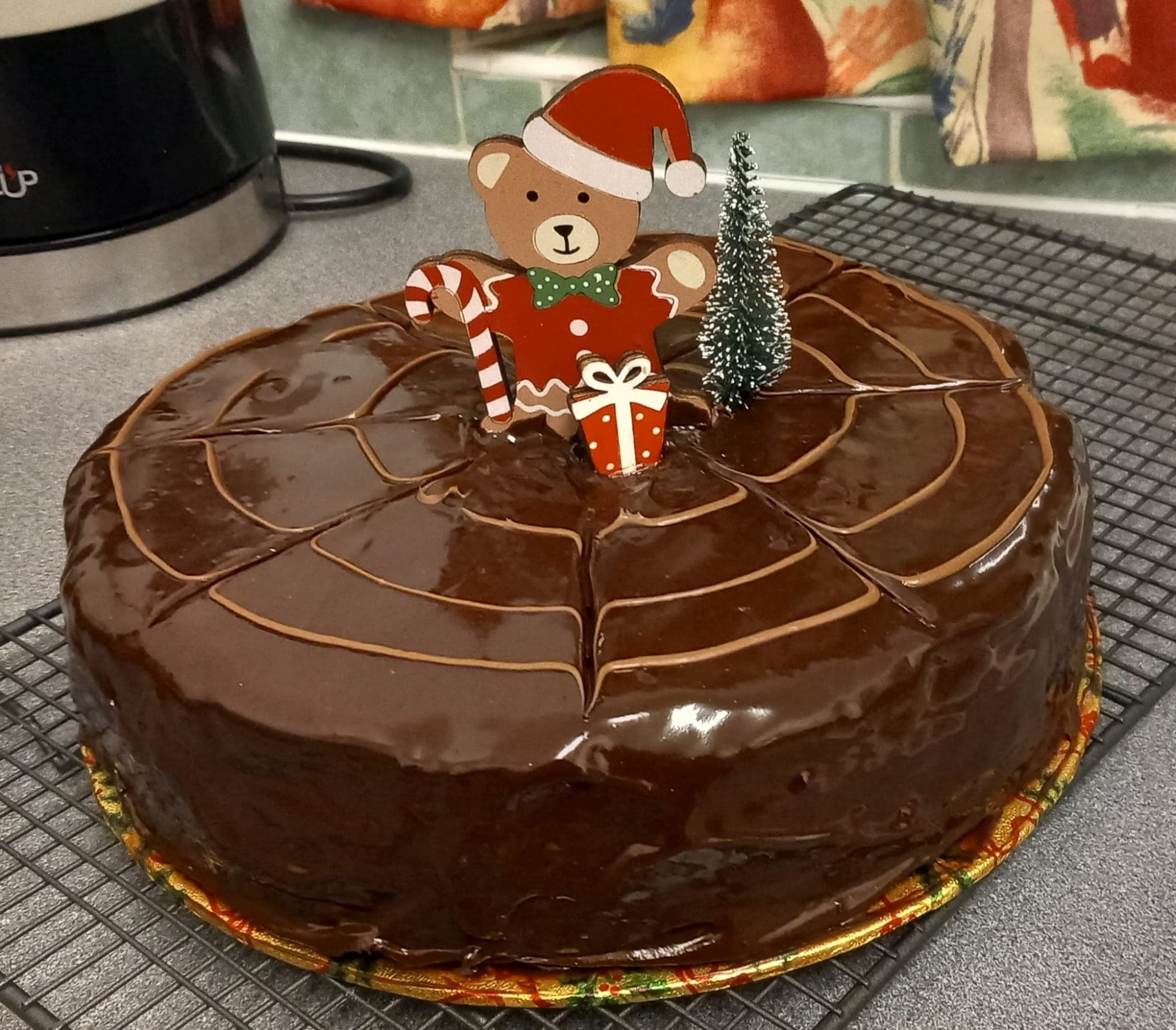 A chocolate cake with a glossy feathered ganache and Christmas decorations