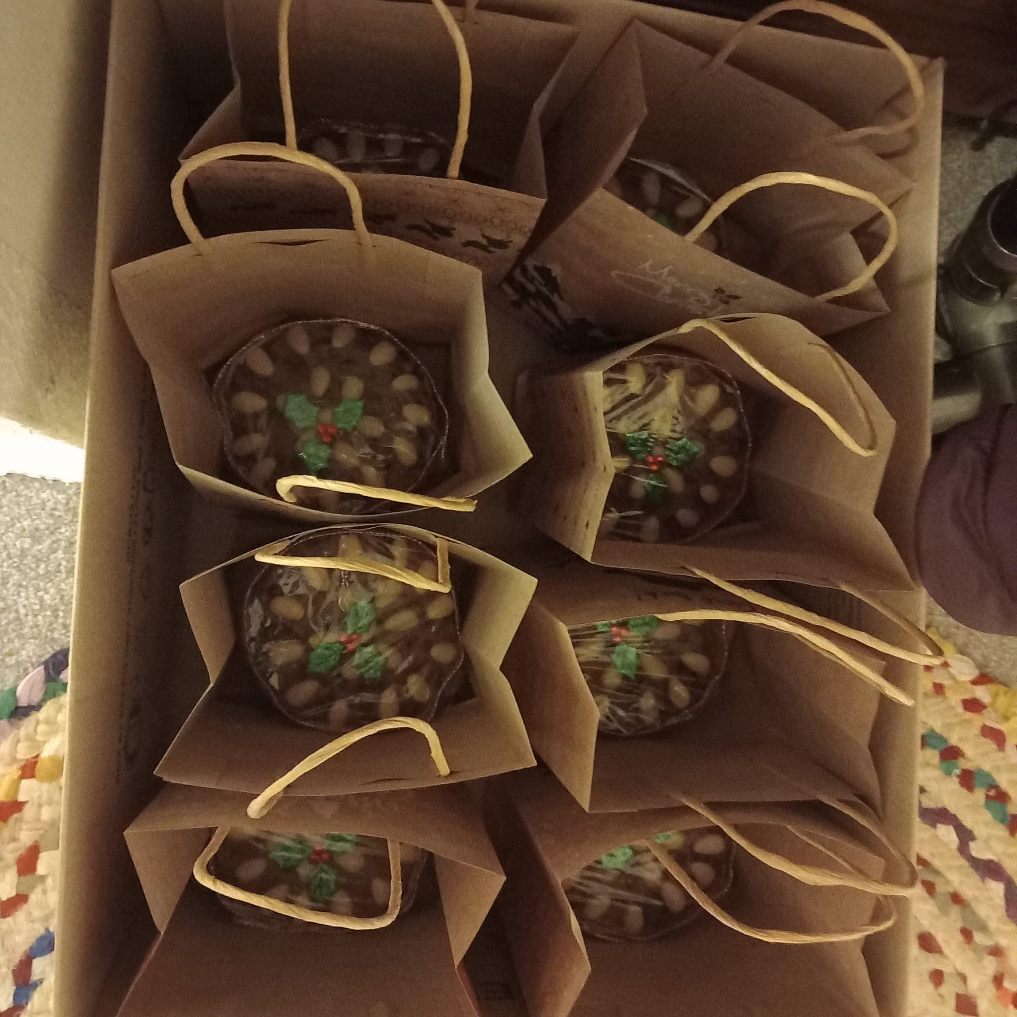 Christmas cakes topped with almonds and holly, wrapped in paper gift bags