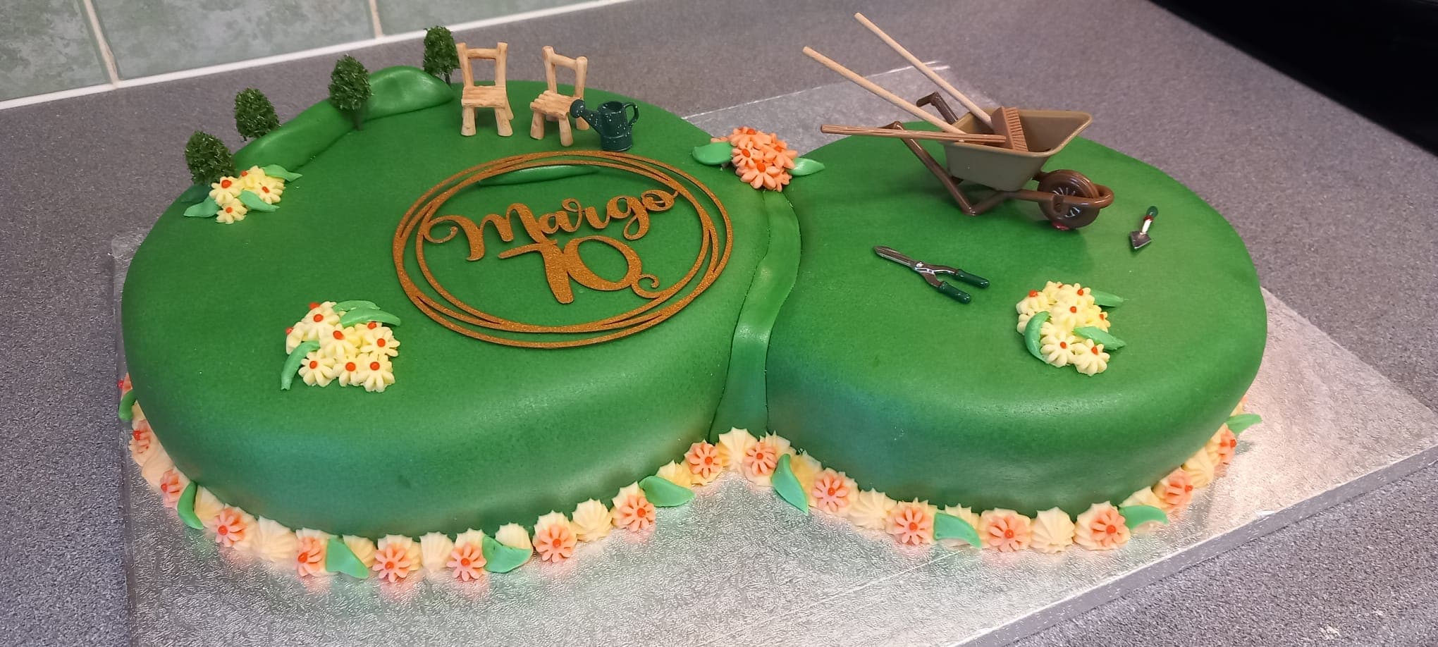 A garden-themed 70th birthday cake with piped flowers and miniature garden tools